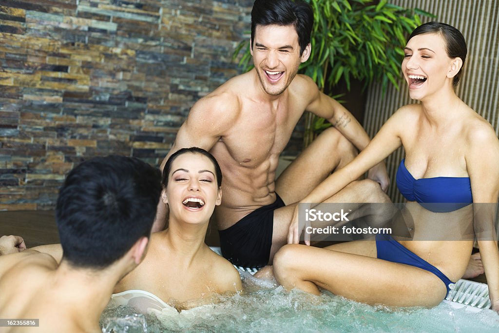 Amici che si diverte con vasca idromassaggio jacuzzi - Foto stock royalty-free di Bagno caldo