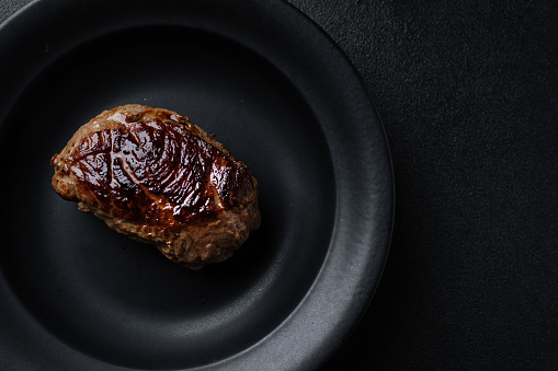 Tasty grilled steak served on dark. Closeup