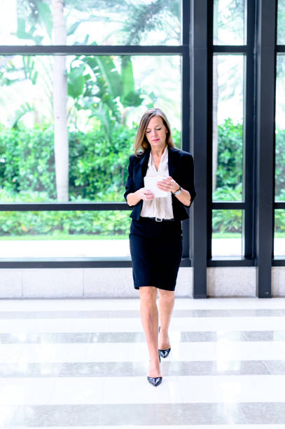 istock Professional woman in her mid-50’s with tablet  in an office setting working on the go 1623572468