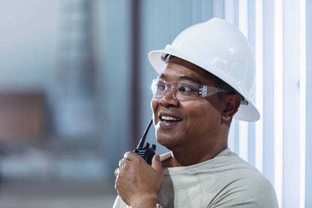 istock Man at construction site in white hardhat on walkie-talkie 1623610931