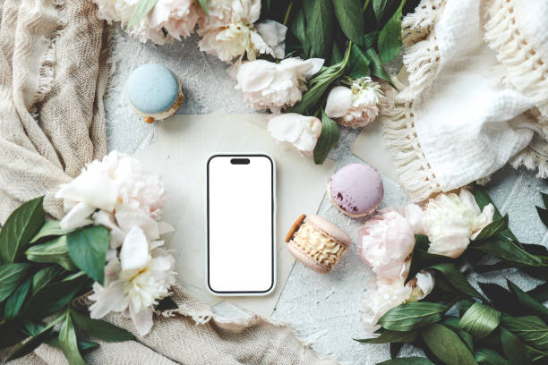 istock Phone with an isolated screen with a place for your advertising, macaroons and peonies 1623638121