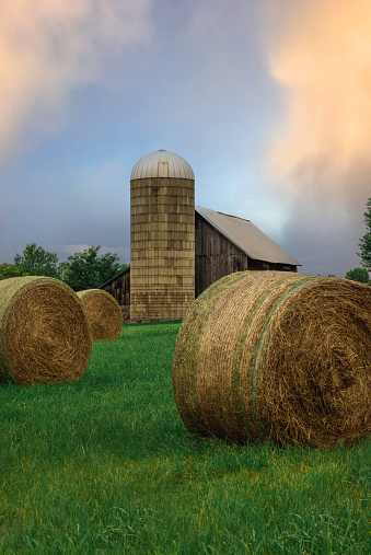 Bales of hay sit in front of a silo and barn in upstate Vermont