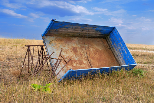abandoned agricultural trailer in dry grass