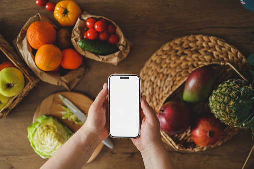 Phone in hands with an isolated screen on the background of the kitchen, the concept of counting calories and proper nutrition.