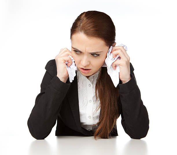 Young woman sitting at a desk, with grimace of anger stock photo