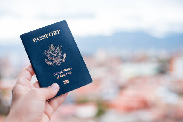 istock One single hand holding a blue American passport in front of a blurry background 1623766672