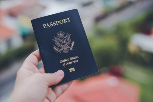 istock One single hand holding a blue American passport in front of a blurry background 1623767725
