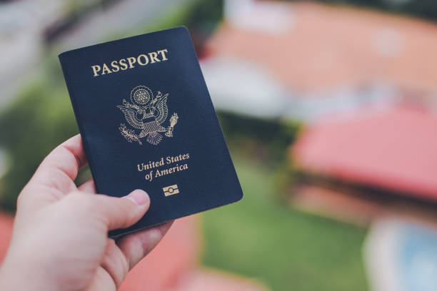 istock One single hand holding a blue American passport in front of a blurry background 1623767728
