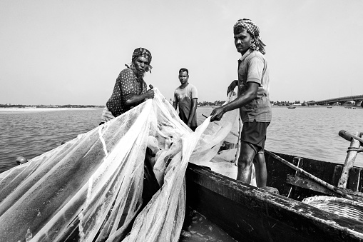 Mandarmani, West Bengal, India, 08/14/2023: Fisher man of Mandarmani, West Benagal, india are prepairing themselves as well as manual fishing boat for fishing in Bay of Bengal, sailing boat in ocean, collecting fishes and spreading fishing net in ocean . Mandarmani is a fishing village. 
Mandarmani is a seaside resort village in the state of West Bengal, India, and lies in East Midnapore district, at the northern end of the Bay of Bengal. It is one of the largest seaside resorts of West Bengal, It is almost 172 km from Kolkata Airport on the Kolkata - Digha route. Red crabs crawling around the 13 km long beach is a special attraction of Mandarmani. It was argued to be the longest driveable (drive in) beach in India.It is located under Contai Sub division area.