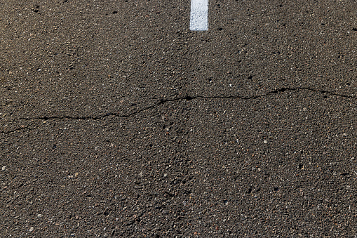 close up shot of yellow arrow sign on cracked asphalt road