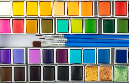 Colourful macro watercolor color box with painting brushes in detail