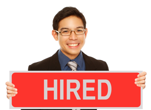 A young man in business attire holding a sign indicating that he found a job