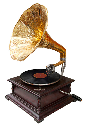 High angle view of a LP record player playing music at home. Old turntable device with LP disc playing retro music on side cabinet with potted plants in living room.