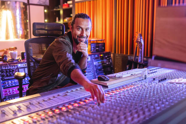 A Smiling Black Male Audio Engineer Readjusting The Sound While Looking At The Camera In A Recording Studio