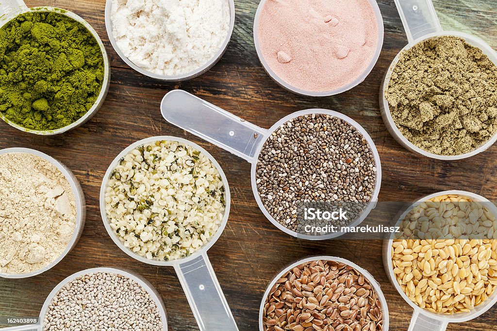 scoops of superfood scoops of superfood - healthy seeds and powders (white and brown chia, brown and golden flax, hemp, pomegranate fruit powder, wheatgrass, hemp and whey protein, maca root) - top view Protein Drink Stock Photo