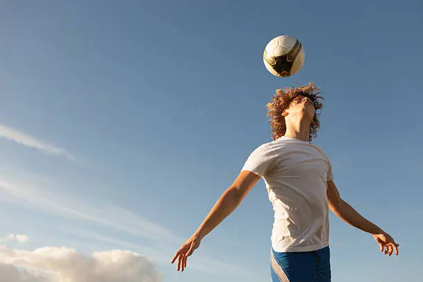 Male soccer player jumping up to head the ball.