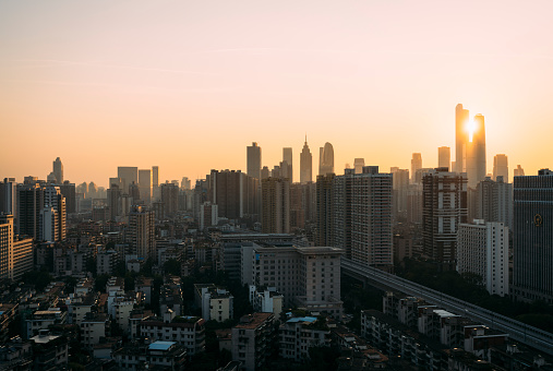 At sunset, the Guangzhou city skyline is covered in golden hues, featuring the residential areas of Yuexiu District and the central business district of Zhujiang New Town in the frame. The Guangzhou Inner circle Expressway cuts through the scene from the middle.
