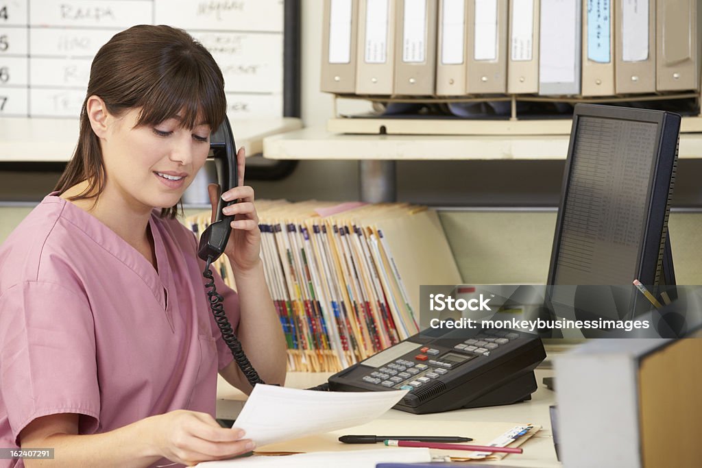 Nurse Making Phone Call At Nurses Station Nurse Making Phone Call At Nurses Station In Hospital Receptionist Stock Photo