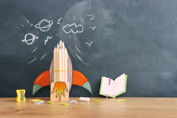 istock Back to school concept. rocket and pencils over classroom blackboard. Top view 1624096284