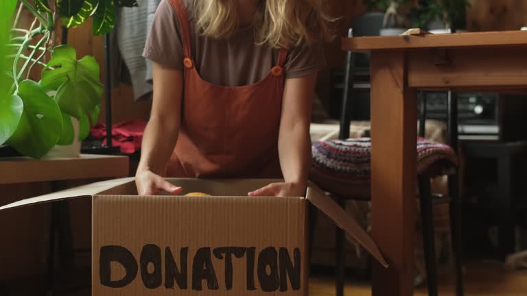 Woman packing apparel into donation box at home.