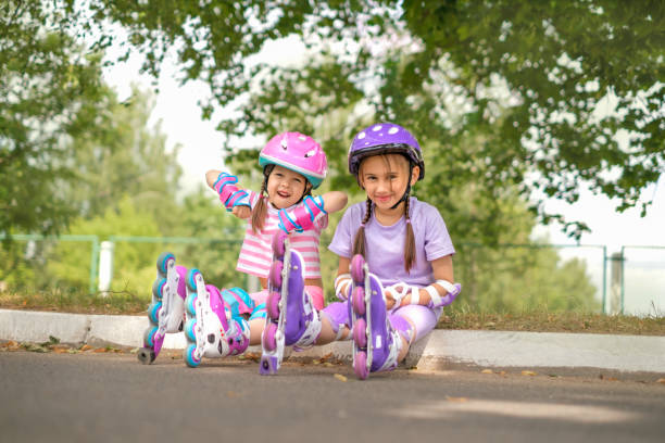Preschool kids in Protective accessories relax on grass after roller skating