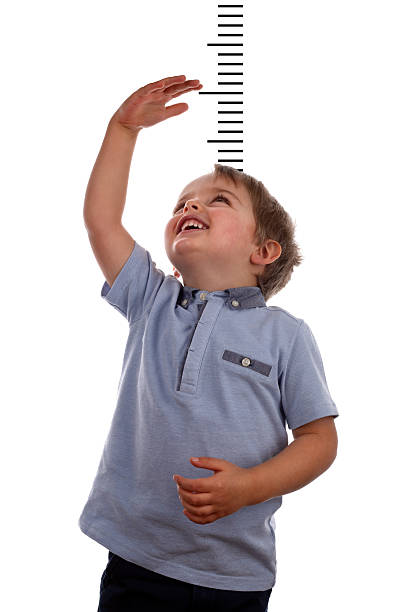 Growing up Young boy measuring his growth in height boy height measure stock pictures, royalty-free photos & images