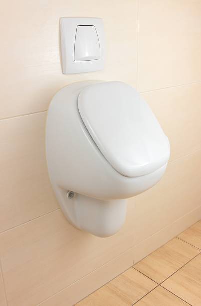 white urinal on beige tiled wall stock photo
