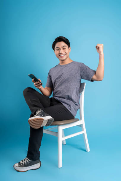 istock Full body young  Asian man using phone on blue background 1624181945