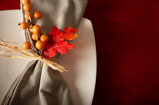 Up close of grey table napkin with berries on red placemat