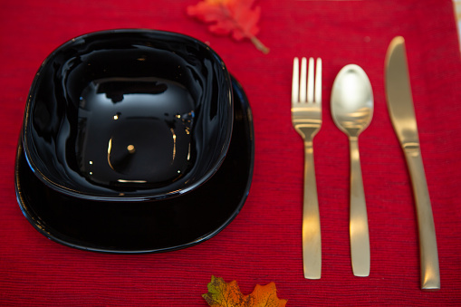 Black bowl and plate with gold utensil on red placemat