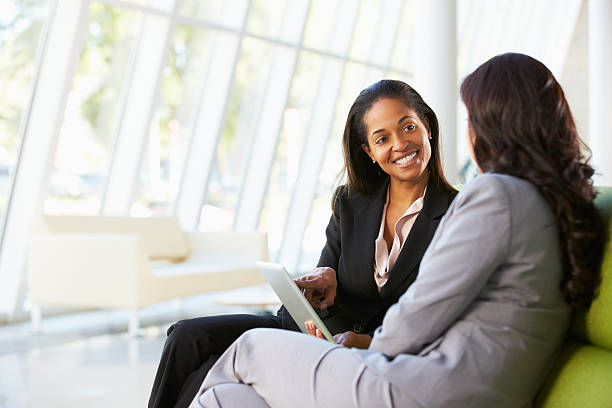 femmes d'affaires avec tablette numérique assis dans le bureau - business relationship business meeting business meeting photos et images de collection