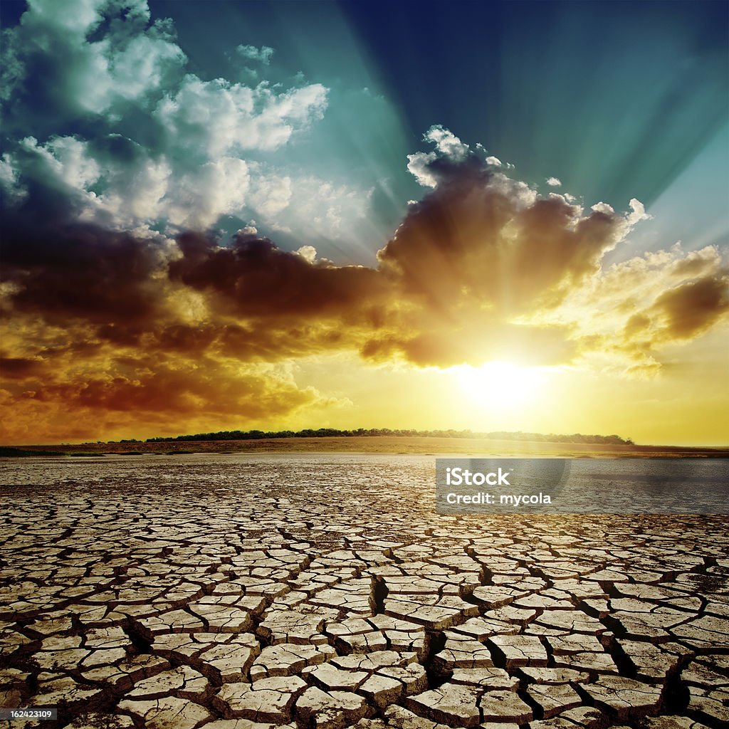 dramatic sunset over cracked earth global warming. dramatic sunset over cracked earth Arid Climate Stock Photo
