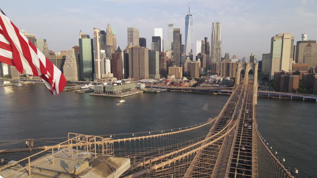 Aerial Shot of The American Flag flying above The Brooklyn Bridge
