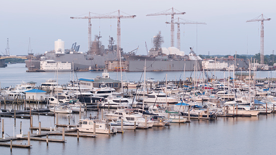 The sterns of HMAS Brisbane (right) and HMAS Canberra (left) of the Royal Australian Navy.  They are docked at Garden Island, Sydney Harbour.  The serial number of each ship is painted on the far stern. HMAS Brisbane is one of three Hobart Class destroyers in the fleet.  HMAS Canberra is one of two Amphibious Assault Ships in the fleet.  This image was taken on a sunny afternoon on 20 May 2023.