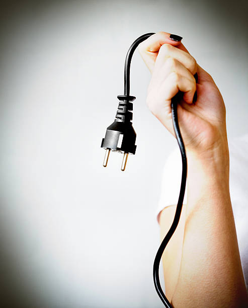 Woman hand holding black electric cable with plug Type F Energy savingblack european plug in male hand on white power cable photos stock pictures, royalty-free photos & images