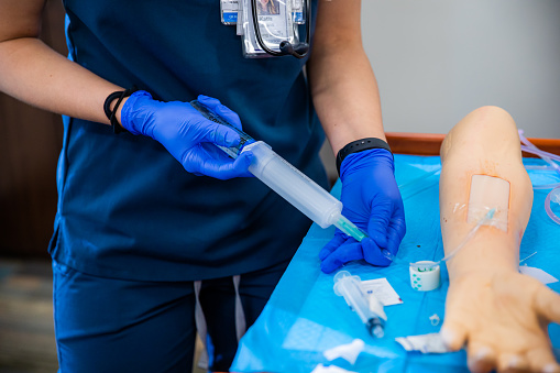 A student practicing medicine injections on a fake arm