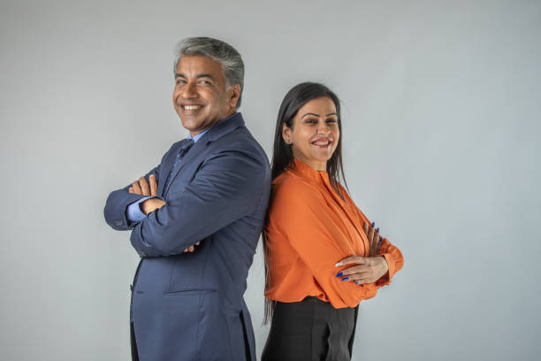 Smiling business partners standing back to back on white background