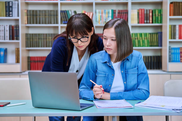 istock Female university student with teacher preparing for exam, inside library 1624439648