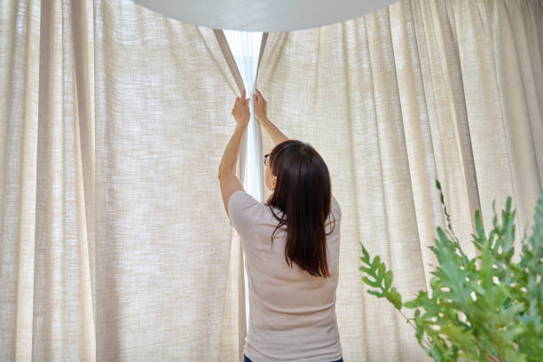 istock Back view, woman opens light curtains in the living room 1624442230
