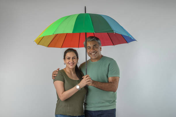 istock Smiling couple with umbrella standing on white background 1624460482