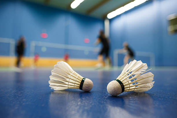 badmintonplätze mit spielern konkurrierende; shuttlecocks im vordergrund - federball stock-fotos und bilder