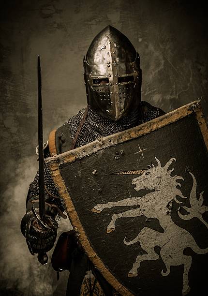Medieval knight with sword and shield against stone wall stock photo