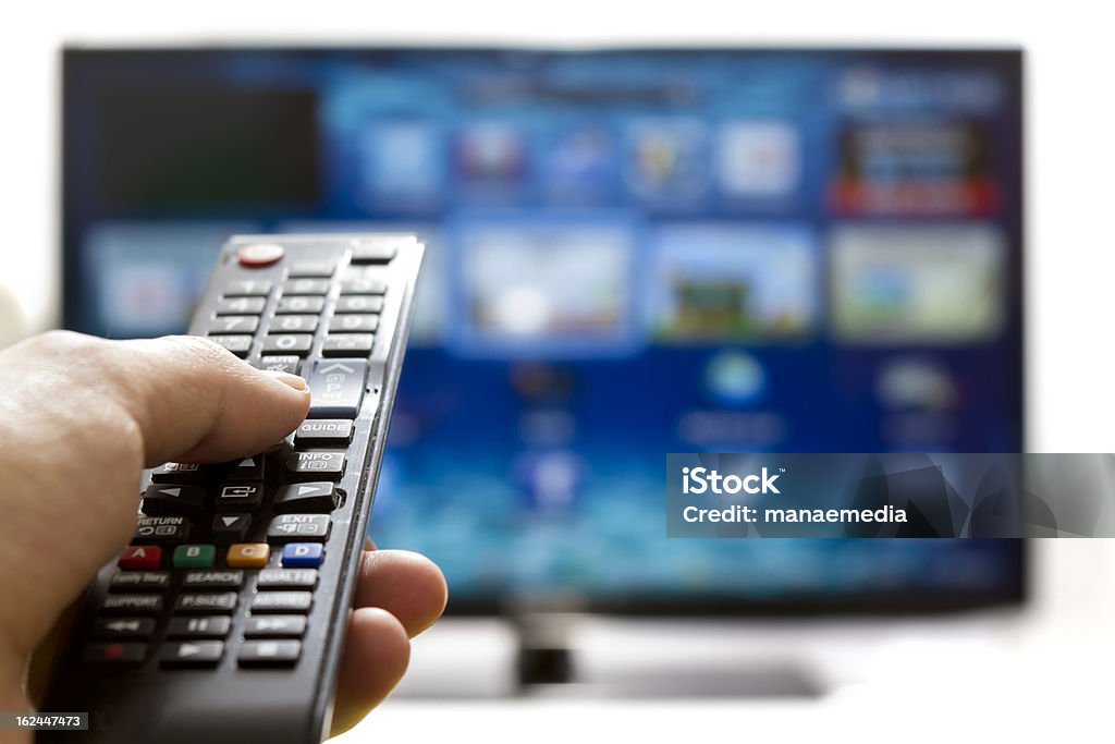 Smart tv and hand pressing remote control Television remote control changes channels thumb on the blue TV screen Television Set Stock Photo