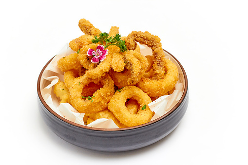 Calamari (deep-fried sliced squid rings) are beautifully decorated with flowers and parsley leaves and served with jagged French fries in a large bowl isolated on white background. Popular Appetizer.