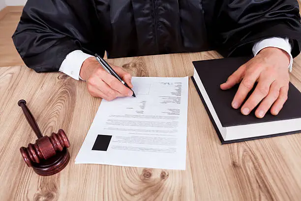 Photo of Close up photo of a robed judge signing a document