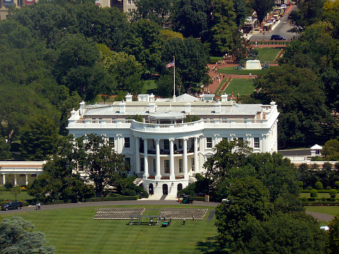 Aerial view of the White House in the summer, an event being set up on the South Lawn, Lafayette Park in the background.