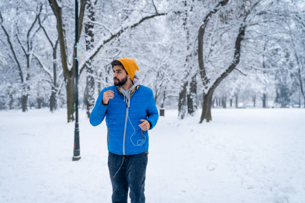 joven decidido hombre guapo corriendo en el parque de la ciudad en el frío día de invierno - fresh snow audio fotografías e imágenes de stock