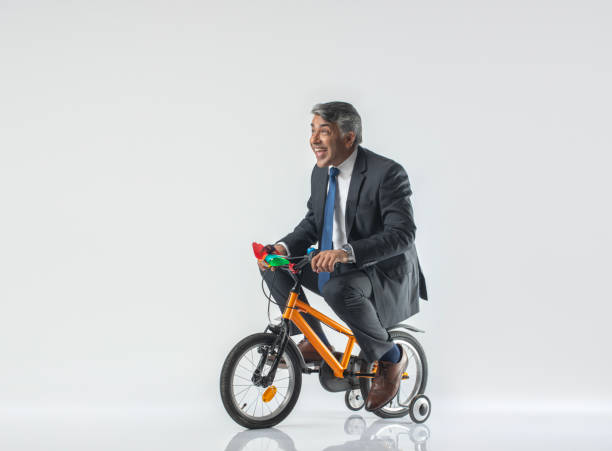 istock Happy senior businessman riding bicycle on white background 1624595133