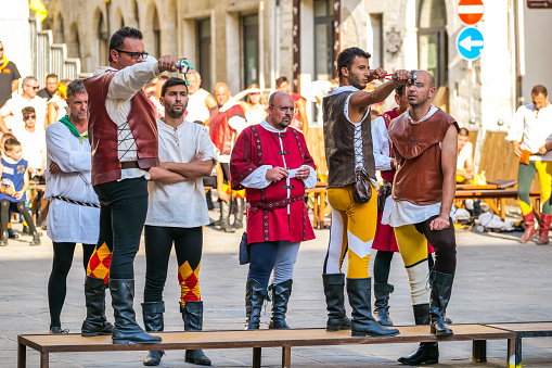 Gualdo Tadino, Umbria, Italy, August 17 -- Some slingers compete during the traditional medieval games in the small town of Gualdo Tadino, in Umbria, central Italy. The slingers are dressed in traditional medieval clothes and represent the different historic districts of the town. The Umbria region, considered the green lung of Italy for its wooded mountains, is characterized by a perfect integration between nature and the presence of man, in a context of environmental sustainability and healthy life. In addition to its immense artistic and historical heritage, Umbria is famous for its food and wine production and for the high quality of the olive oil produced in these lands. Image in high definition quality.