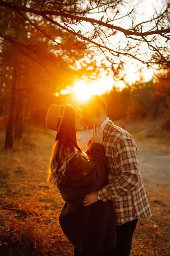 Happy couple of lovers in casual clothes walk, travel together through the autumn forest at sunset. The concept of people, recreation. Lifestyle.